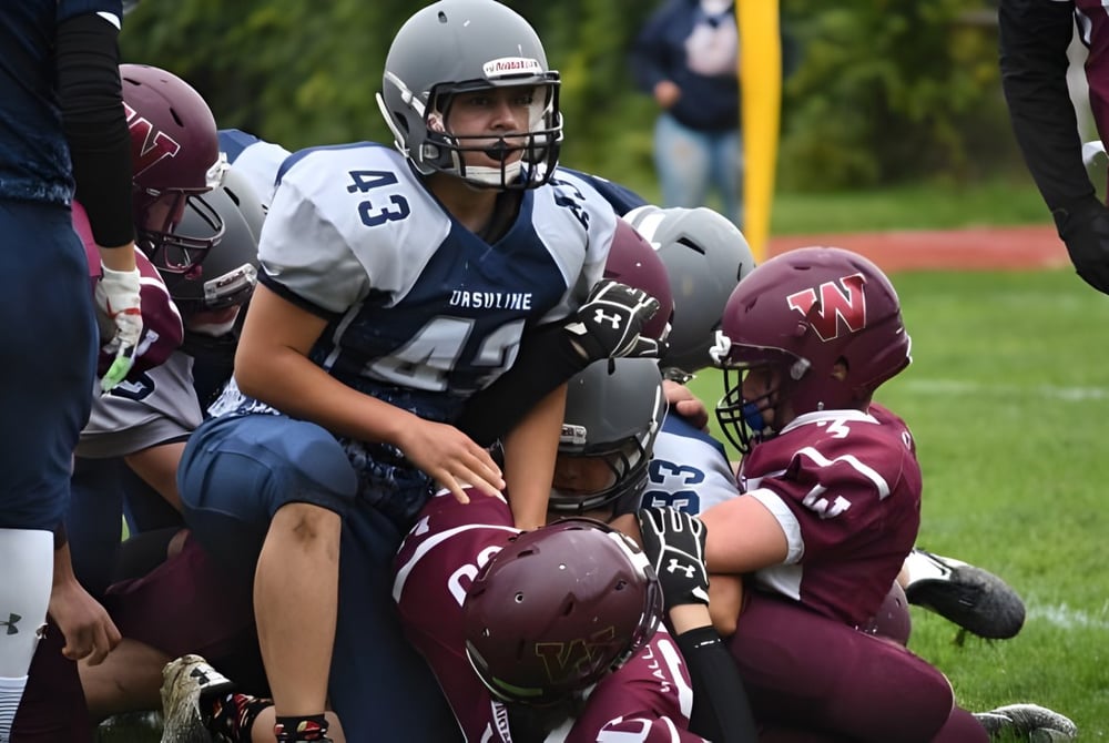 Schüler der Wallaceburg District High School spielen ein Footballspiel mit Tackle auf dem Spielfeld.