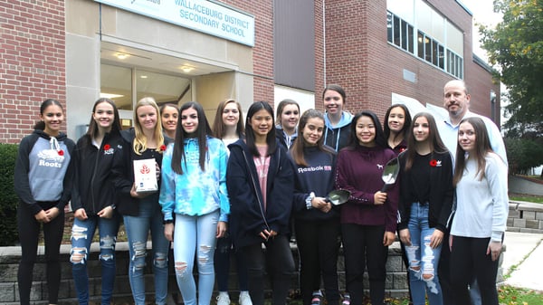 Eine Gruppe von Schülerinnen und Schülern steht vor dem Backsteingebäude der Wallaceburg District High School.