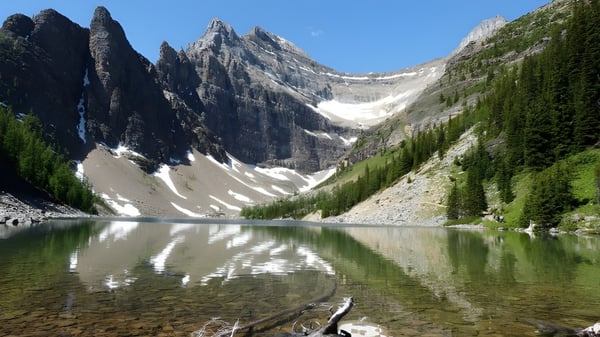 Ein alpiner See mit schneebedeckten Bergen und bewaldeten Hängen auf dem Gelände der Walnut Grove Secondary School.
