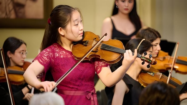 Eine Schülerin der Walnut Hill School for the Arts spielt Violine auf der Bühne zusammen mit anderen Musikern.