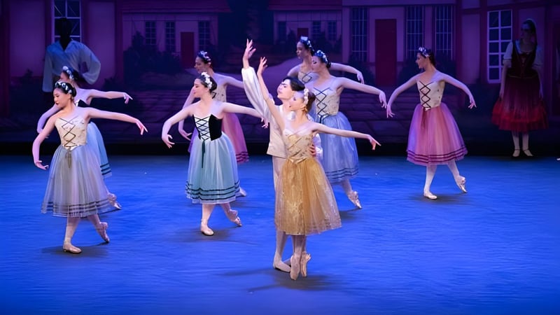 Schülerinnen der Walnut Hill School for the Arts führen in farbenfrohen Kostümen ein Ballett auf einer Bühne mit reich verzierten Architektur-Elementen auf.