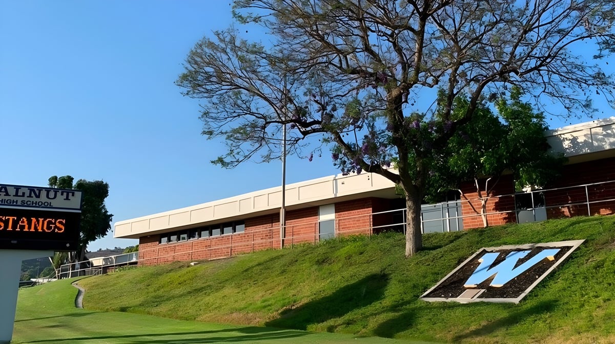 Das Backsteingebäude mit einem großen W-Zeichen auf einem grasbewachsenen Hang im Walnut Valley School District.