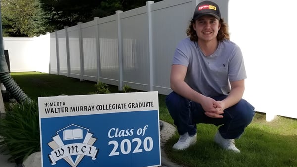 Ein Schüler sitzt neben einem Schild der Walter Murray Collegiate Graduate Class of 2020.