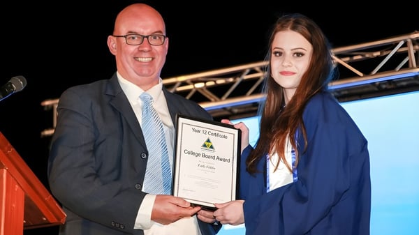 Ein Mann und eine Frau in formeller Kleidung bei der Übergabe eines Zertifikats auf dem Campus der Wanneroo Secondary College.