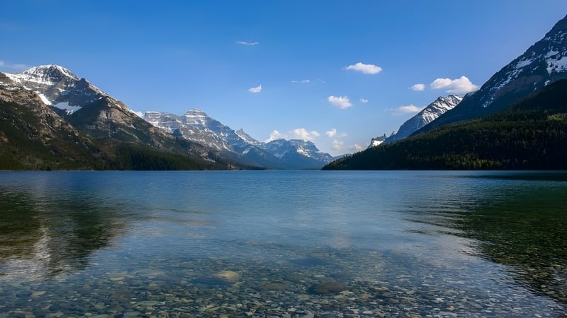 Ein alpiner See mit spiegelglatter Oberfläche und schneebedeckten Bergen im Hintergrund nahe der Warburg School.