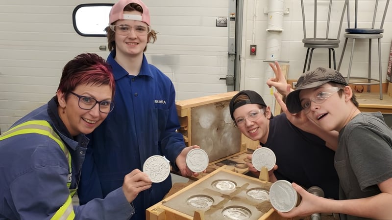 Schüler der Warburg School arbeiten in der Werkstatt und untersuchen Keramikstücke an einem Holztisch.