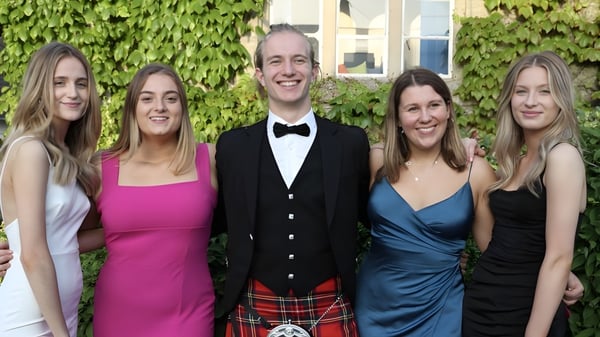 Eine Gruppe von fünf Personen steht formell gekleidet vor einer grün bewachsenen Wand auf dem Gelände der Warminster School.