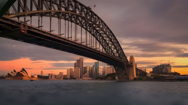 Sonnenuntergang über der Sydney Harbour Bridge mit Skyline und Opernhaus im Hintergrund, gesehen von Warners Bay High School.