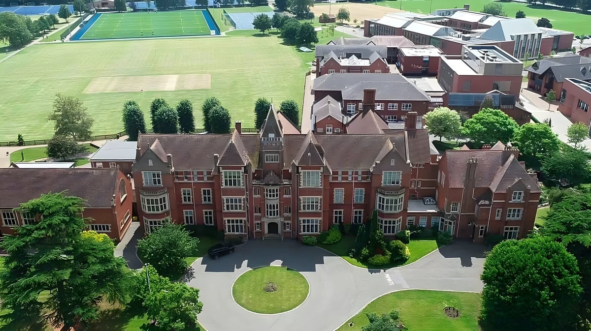 Das historische Hauptgebäude der Warwick School mit einem runden Vorplatz und grünen Rasenflächen im Vordergrund.