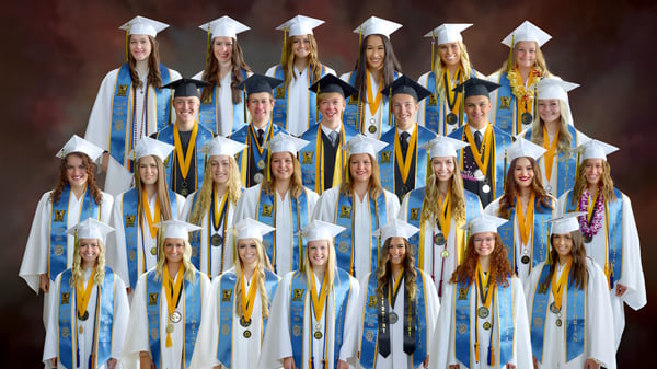 Eine Gruppe von Absolventen der Wasatch Academy in blauen und gelben Talaren vor rotem Hintergrund.