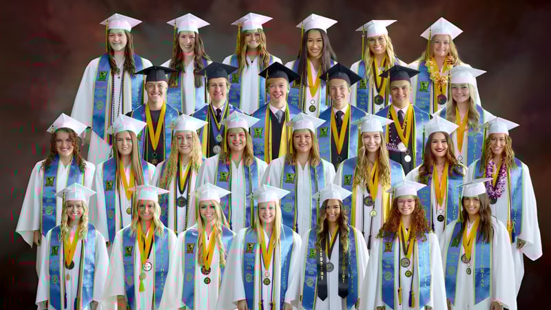 Eine Gruppe von Absolventen der Wasatch Academy in blauen und gelben Talaren vor rotem Hintergrund.
