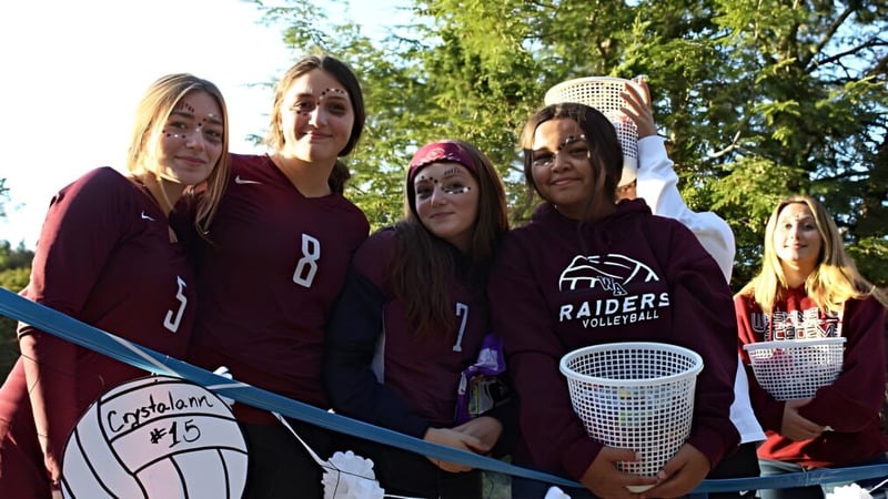Eine Gruppe Schülerinnen der Washington Academy steht im Wald mit einem Volleyballnetz in den Händen.