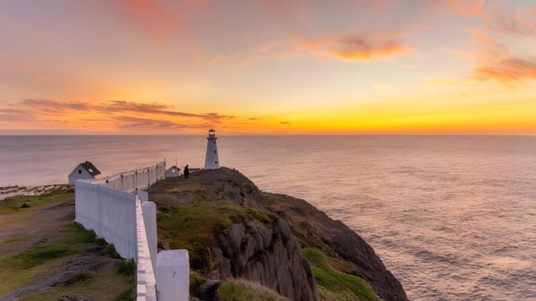 Ein Leuchtturm steht auf einer felsigen Klippe mit Blick auf das Meer bei Sonnenuntergang nahe der Waterford Valley High School.