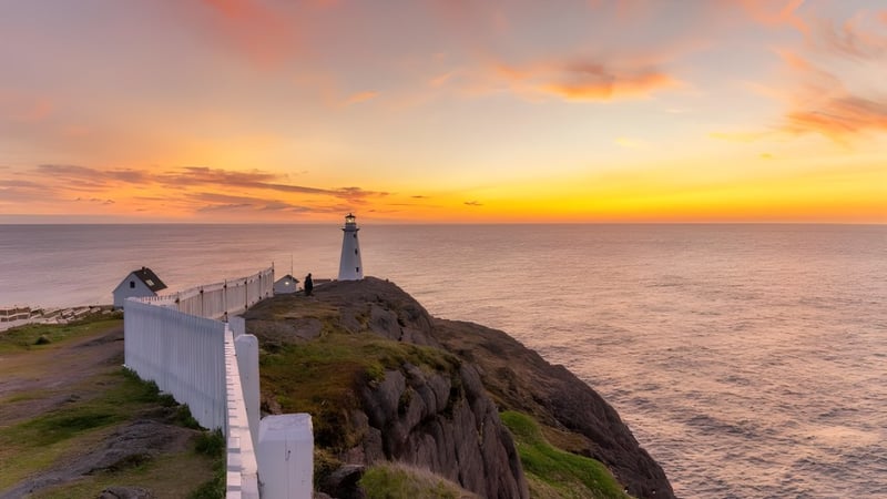 Ein Leuchtturm steht auf einer felsigen Klippe mit Blick auf das Meer bei Sonnenuntergang nahe der Waterford Valley High School.