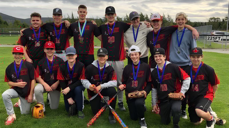Eine Gruppe junger Sportlerinnen und Sportler posiert auf dem Sportplatz der Waterford Valley High School vor einer Bergkulisse.