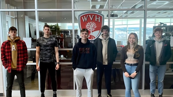 Eine Gruppe Schüler steht vor dem großen WVH-Logo im Gebäude der Waterford Valley High School.