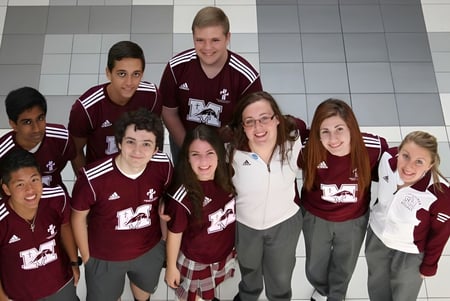 Eine Gruppe Schüler mit gleichen burgunderfarbenen Trikots steht gemeinsam im Flur der Waterloo Catholic District School Board.