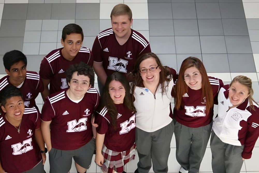 Eine Gruppe Schüler mit gleichen burgunderfarbenen Trikots steht gemeinsam im Flur der Waterloo Catholic District School Board.