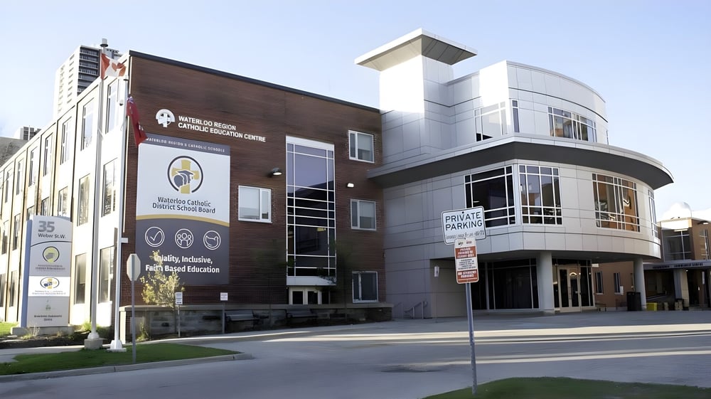 Das moderne mehrstöckige Gebäude mit Backsteinfassade und Eingangsbereich gehört zum Waterloo Catholic District School Board und ist von Grünflächen umgeben.