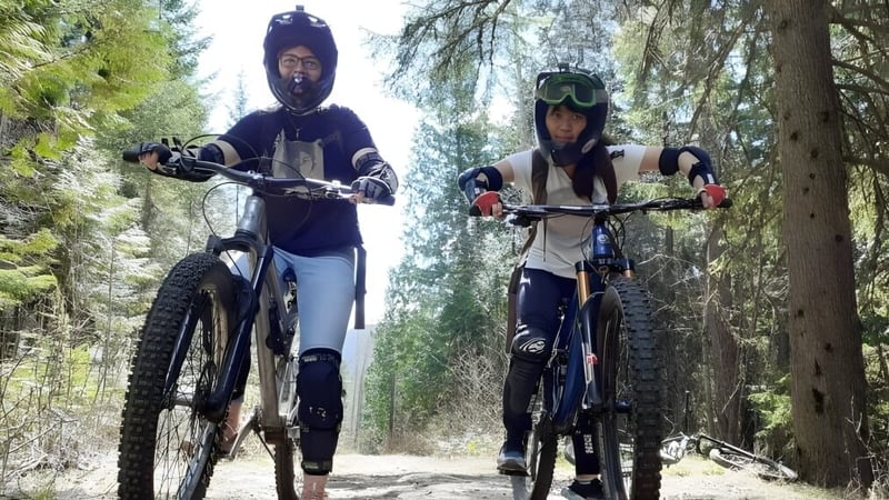 Zwei Personen vom Waterloo Region District School Board fahren mit Schutzkleidung Mountainbike auf einem Waldweg.