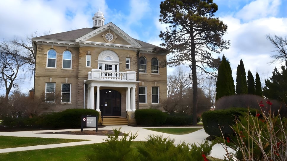 Das historische Hauptgebäude der Wayland Academy steht umgeben von einem gepflegten Garten mit Bäumen und Sträuchern.