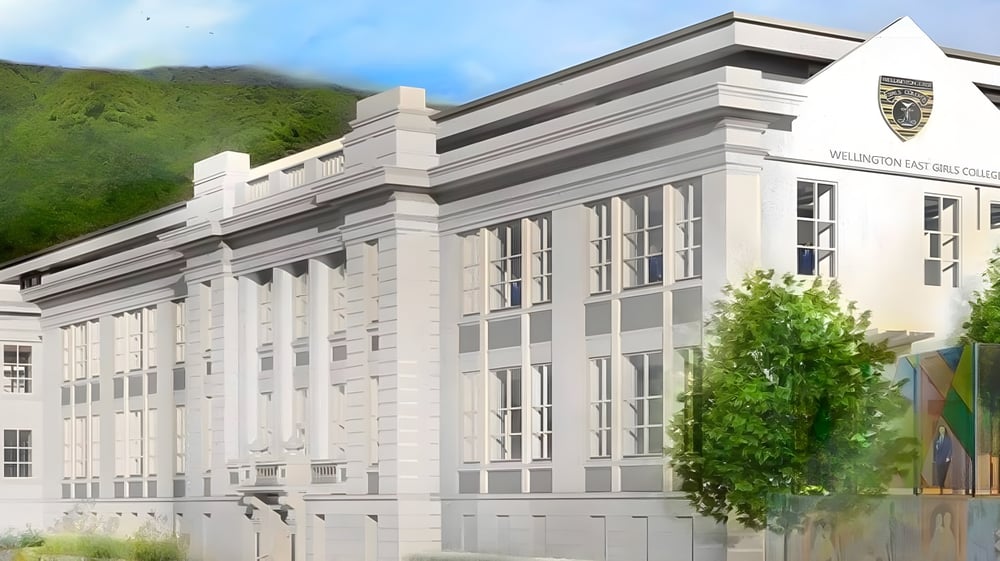 Das große weiße Gebäude des Wellington East Girls’ College ist von grüner Natur und Bergen im Hintergrund umgeben.