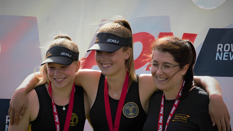 Drei Schülerinnen des Wellington Girls' College posieren gemeinsam vor einem bunten Hintergrund.