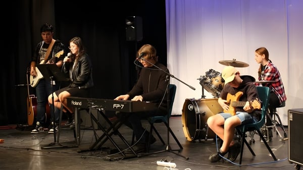 Eine Gruppe von Musikerinnen und Musikern der Wellington Point State High School tritt auf der Bühne mit verschiedenen Instrumenten auf.
