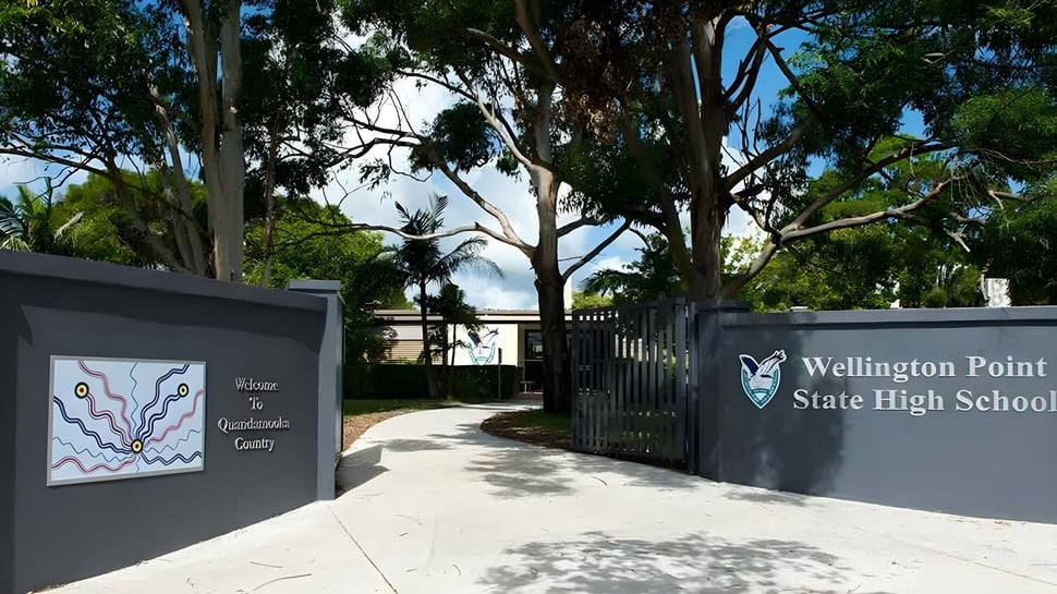 Der Eingang zur Wellington Point State High School mit dem Schulgebäudeschild und umgeben von Bäumen und Pflanzen.