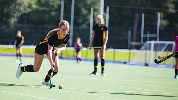 Eine Gruppe von Hockeyspielerinnen dribbelt und spielt auf dem Kunstrasenfeld der Wellington School.