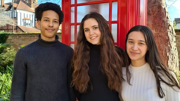 Drei junge Menschen stehen vor einer roten Telefonzelle auf dem Gelände der Wells Cathedral School.
