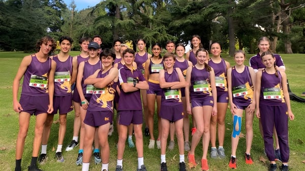 Eine Gruppe junger Athletinnen in lila Uniformen steht auf einer Wiese auf dem Campus von Wesley College.