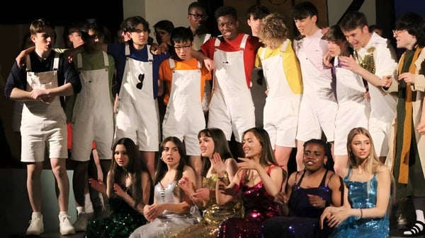 Eine Gruppe von Schülerinnen und Schülern steht auf der Bühne im Wesley College und präsentiert sich in bunten Outfits.