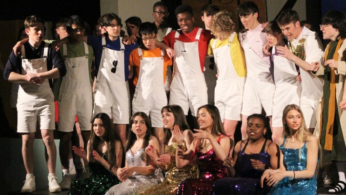 Eine große Gruppe von Schülerinnen und Schülern des Wesley College steht auf einer Bühne während einer Aufführung.