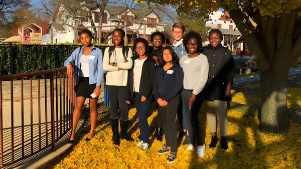 Eine Gruppe von Schülerinnen und Schülern sowie Erwachsenen steht im Freien vor herbstlichem buntem Laub auf dem Gelände der West Nottingham Academy.