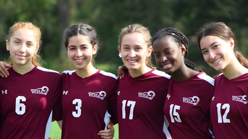 Eine Gruppe von fünf Schülerinnen der West Nottingham Academy steht gemeinsam im Freien auf einer Wiese mit Bäumen im Hintergrund.