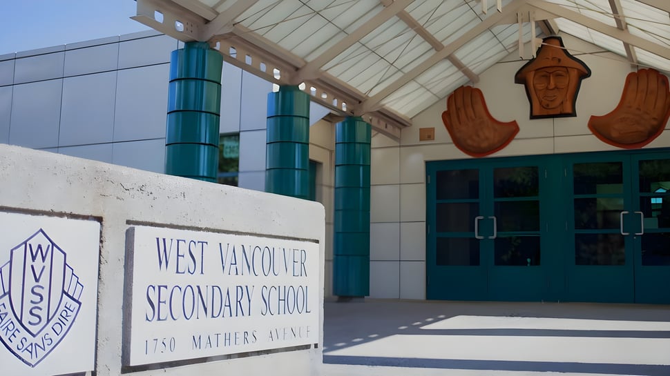 Das Schulgebäude der West Vancouver Secondary School mit markantem Dach und großen Fenstern ist von einem Schild mit Schulname und Adresse umgeben.