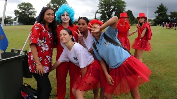 Schüler der Western Heights High School posieren zusammen draußen in bunten Kostümen auf einer Wiese mit Bäumen im Hintergrund.