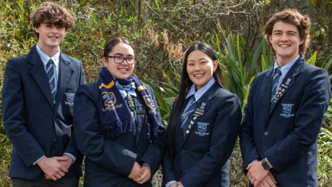 Eine Gruppe von Schülern steht im Freien vor Bäumen auf dem Gelände der Western Heights High School.
