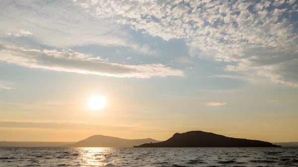 Ein ruhiger Sonnenuntergang mit einer Bergsilhouette und reflektierendem Wasser nahe der Western Heights High School.