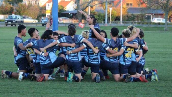 Eine Gruppe junger Athleten in blauen und gelben Trikots trainiert auf dem Sportfeld der Western Heights High School.
