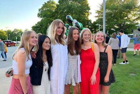 Eine Gruppe von Schülerinnen steht auf dem Außenbereich der Western Michigan Christian School vor Bäumen und Grasfläche.