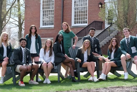 Eine Gruppe von Schülerinnen und Schülern sitzt vor einem Backsteingebäude auf den Stufen auf dem Campus der Western Reserve Academy.