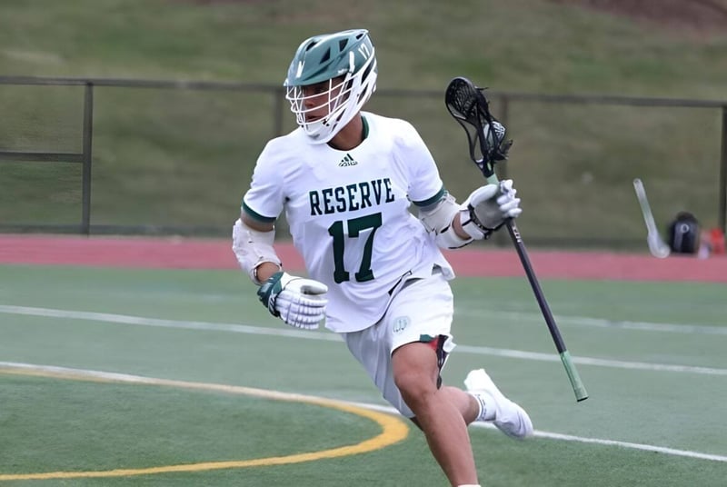 Ein Sportler mit einem weißen Trikot der Western Reserve Academy läuft mit einem Lacrosse-Schläger über das Spielfeld.