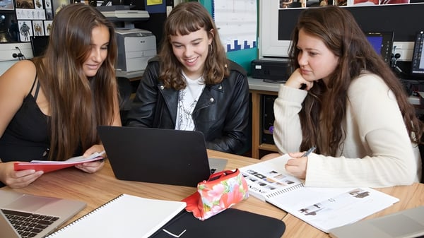 Drei Schülerinnen des Western Springs College arbeiten gemeinsam an einem Laptop in einem Arbeitsraum.