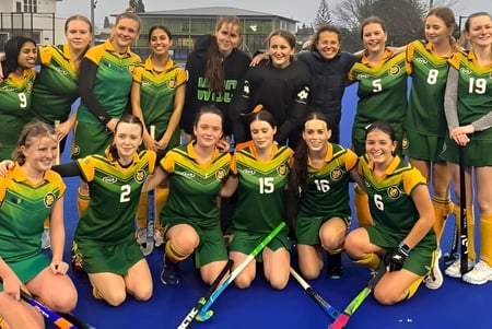 Eine Gruppe junger Sportlerinnen posaert auf dem Sportplatz des Western Springs College vor einem Gebaeude.