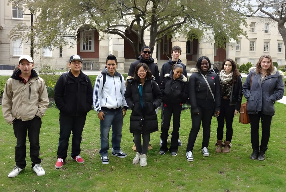 Eine Gruppe von Schülerinnen und Schülern steht vor einem historischen Gebäude auf dem Campus der Western Technical-Commercial School.