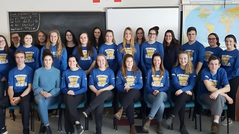 Schüler der Westisle Composite High School sitzen in einem Klassenzimmer mit einer Tafel im Hintergrund.