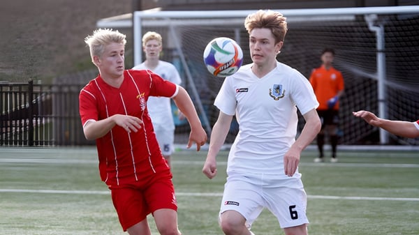 Zwei Schüler der Westlake Boys High School spielen Fußball auf dem Sportplatz und kämpfen um den Ball.