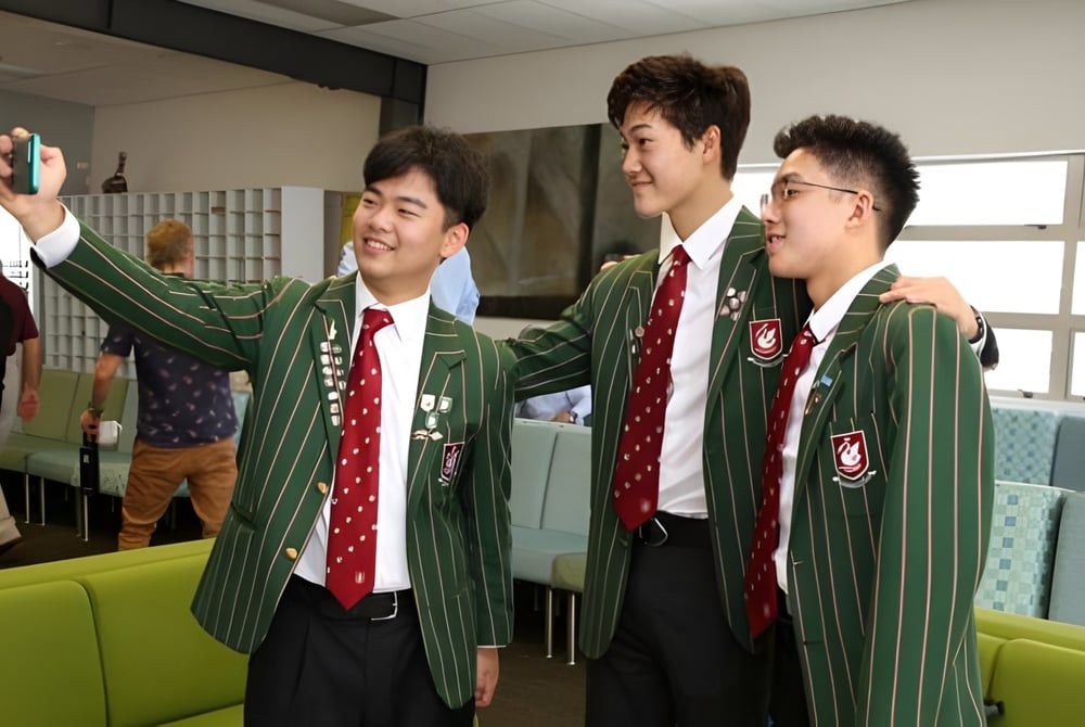 Drei Schüler der Westlake Boys High School in Schuluniformen posieren gemeinsam und lächeln.